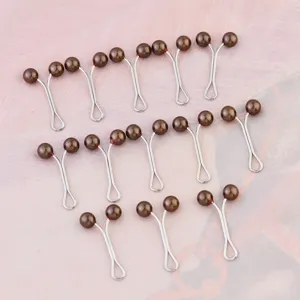 Detail shot of brown pearl hijab scarf clips, metal Y-shaped fixing pins for daily wear.