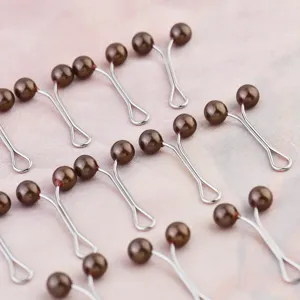 Brown pearl hijab clips detail shot, elegant Y-shaped scarf pins for secure styling.