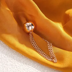 Close-up detail of a elegant rose gold scarf ring with delicate hanging chains on silk.