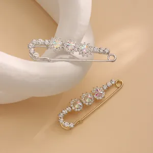 Close-up detail of rhinestone safety pin brooches in silver and gold with colorful crystals.
