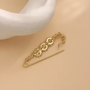 Gold safety pin brooch detail shot, stylish decorative accessory for clothes and shawls.