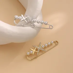 Close-up detail shot of exquisite starfish pearl safety pin brooch in gold and silver finish.