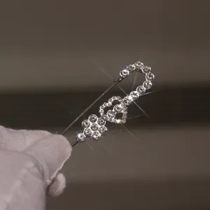 Sparkling rhinestone safety pin brooch detail featuring charming heart and flower elements.