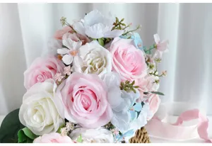 Gros plan de bouquet de mariée artificiel avec roses roses et blanches, détails floraux.