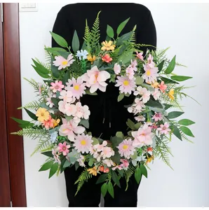 Detailansicht des künstlichen Frühlingsblumenkranzes mit rosa Gänseblümchen und grünen Blättern.