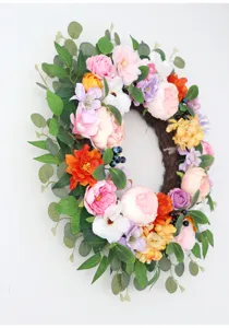 Artificial floral wreath detail with mixed peonies, roses, and eucalyptus leaves for home decor.