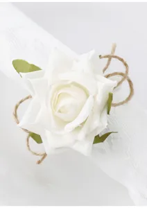 Primo piano dettagliato di un portatovagliolo con rosa artificiale bianca e corda.