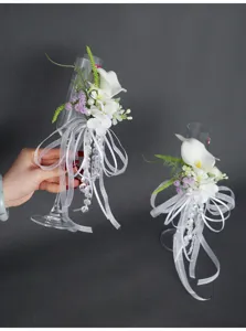 Nahaufnahme Detail des Hochzeitssektglases mit künstlicher Calla-Lilie und weißer Schleife.