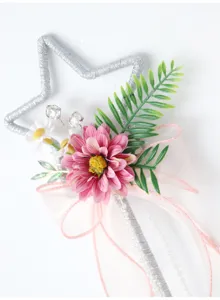 Primo piano dei dettagli della bacchetta magica con fiore rosa e stella argentata.
