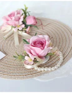 Detailansicht von künstlicher rosa Rosen-Korsage und Perlen-Armbandblume für Hochzeitsbraut.