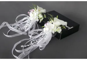 Detailansicht künstlicher Calla Blumen für Hochzeit und Gläser mit weißen Bändern und Perlen.