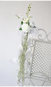 Artificial white flower chair back decor with ribbons for wedding party event decor detail view