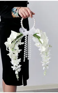 Detalle de ramo de novia con calas blancas y mango de perlas para decoración floral.