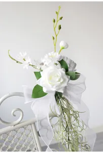 White artificial flower chair back decoration for wedding party event venue decor detail.