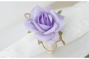 Portatovaglioli con rosa artificiale viola e corda di juta per decorazione tavola.