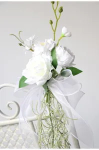 Close-up detail of white artificial wedding chair back flower with elegant organza ribbon.