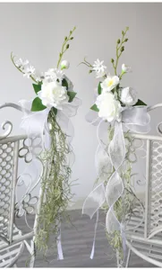 Wedding chair back artificial flowers with white roses and hanging vines for party decor.