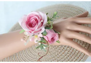 Nahaufnahme des rosa künstlichen Rosen-Armbandes mit grünen Blättern für die Hochzeit.