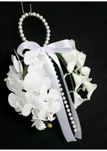Primer plano del detalle de ramo de orquídeas y calas artificiales con perlas y lazo blanco.