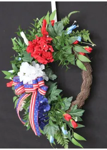 Close-up van kunstmatige hortensiakrans met rood-wit-blauwe patriotische lint en groene bladeren.