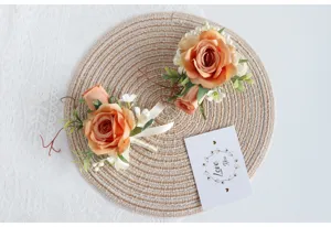 Nahaufnahme einer künstlichen Champagner-Rosen-Ansteckblume mit grünen Blättern und Schleife.