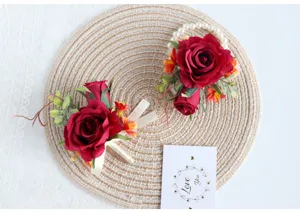 Detailansicht des roten Rosen Hochzeitskorsetts und Perlen Armbands auf geflochtener Matte.