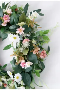 Primo piano dettagliato di ghirlanda di fiori artificiali con fiori rosa e foglie.