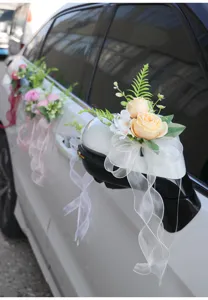 Detail view of artificial wedding car mirror flower decoration with champagne roses and white bow.