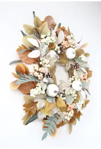 Close-up detail of autumn wreath with white pumpkins, pinecones, and fall foliage for door decor.