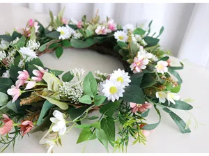 Dettaglio ravvicinato della ghirlanda di fiori artificiali con margherite bianche e foglie verdi.