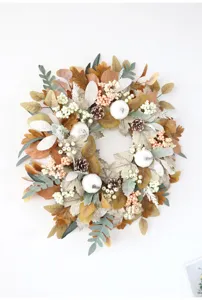 Autumn artificial maple leaf wreath detail featuring white pumpkins and pinecones for wall decor.