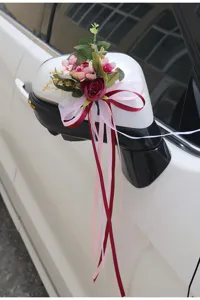 Bruiloft auto achteruitkijkspiegel kunstmatige bloemdecoratie met roze en rode linten.
