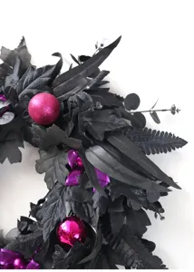 Black artificial Halloween wreath with purple ornaments and maple leaves for door decor.
