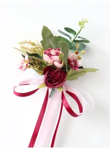 Detailopname van het decoratieve kunstbloemen bruiloftsboeket in roze en bordeauxrood.