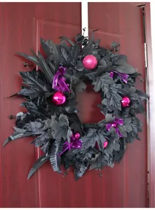 Close-up detail of black Halloween artificial wreath with maple leaves and pink decorative balls.
