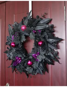 Black artificial Halloween wreath detail, maple leaves and purple baubles door hanging prop.