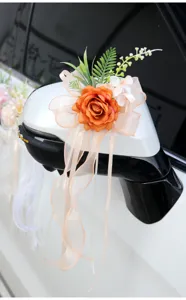 Artificial wedding car mirror flower decoration with orange rose and ribbon bow for ceremony.