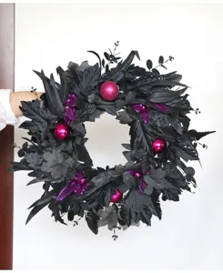 Detailed view of a black artificial Halloween wreath featuring purple ornaments and maple leaves.