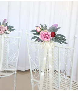 Detailed view of artificial rose wedding chair back flower decoration with white ribbon.