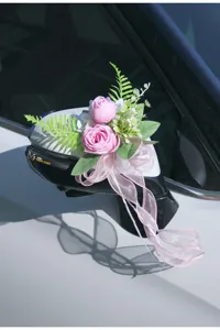 Close-up of car rearview mirror artificial pink rose flower decoration with bow ribbon for wedding.