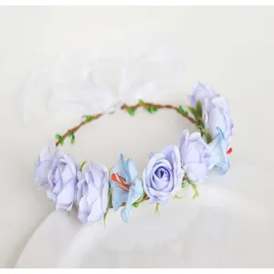 Close-up detail of the fairy floral crown headpiece, blue artificial roses and white ribbons.