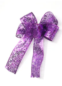 Dettaglio fiocco con nastro glitter viola in primo piano per confezione regalo festa