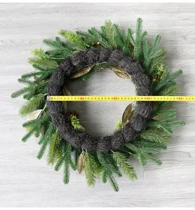 Weihnachtskranz Dekoration mit Tannennadeln, goldenen Blättern und Zapfen für Feiertage.