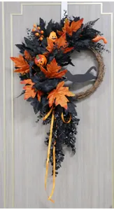Detailed view of Halloween wreath with black and orange leaves, pumpkins, and a cute cat silhouette.