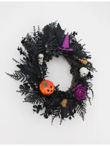 Halloween zwarte krans detail met pompoen, schedels en paarse heksenhoed voor feestdecoratie.
