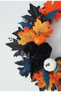 Close-up detail of Halloween artificial wreath featuring black roses and pumpkins for spooky decor.