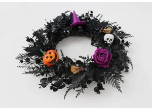 Gedetailleerde close-up van zwarte Halloween-krans met griezelige pompoen- en schedelelementen.