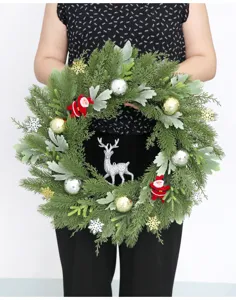 Detalle de corona de Navidad con ramas de pino, esferas y figuras para decoracion festiva.