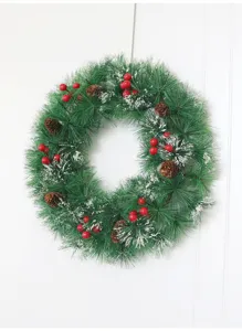 Vista detallada de la corona de navidad con agujas de pino artificiales y bayas rojas.