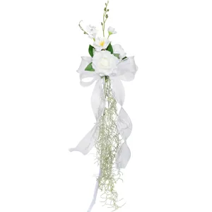 White artificial wedding chair back flower decoration with bow and hanging vine ribbon.